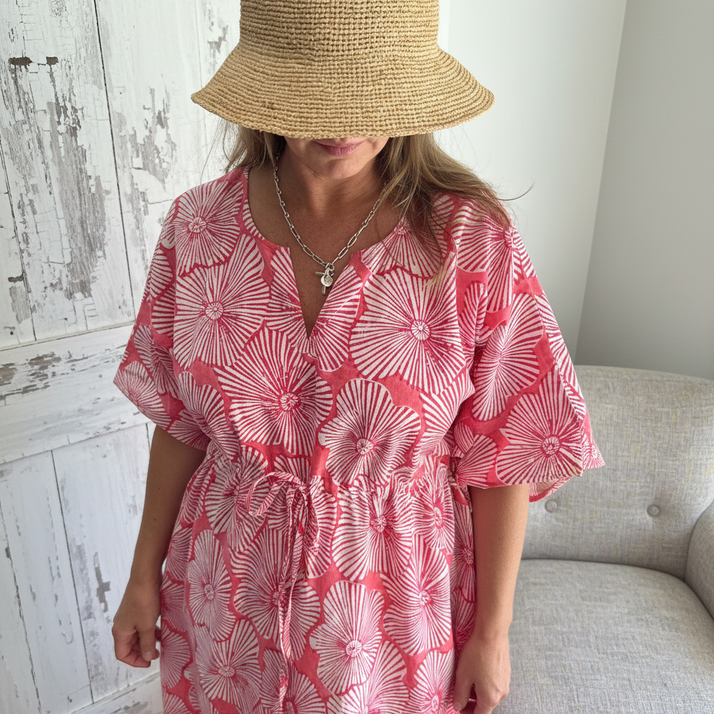 Editorial close-up of coral pink sunburst kaftan in shabby chic setting