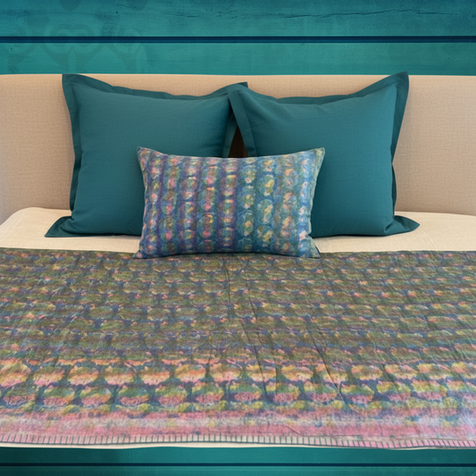 Luxury bedroom setting with teal wall, modern linen headboard, quilt draped over foot of bed showing hand blanket stitch edge