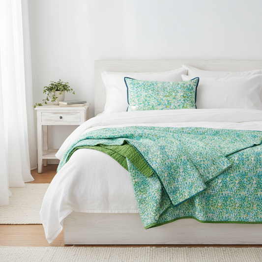 Sea Glass quilt folded at foot of white linen bed with matching cushion